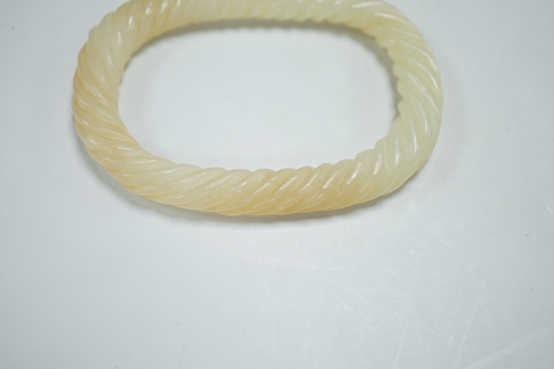 A Chinese pale celadon jade rope twist bangle, 8.3cm wide